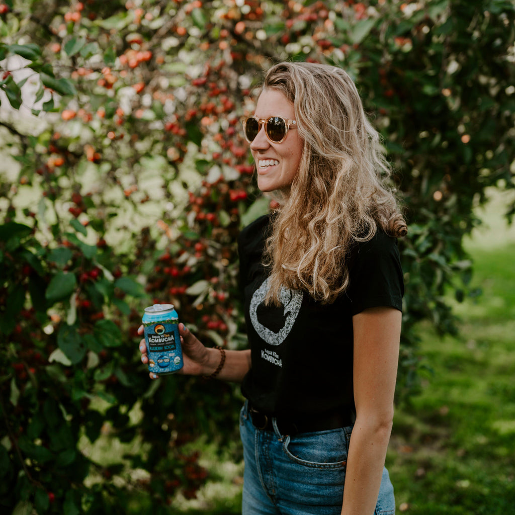 person holding a can of blueberry social in an apple orchard